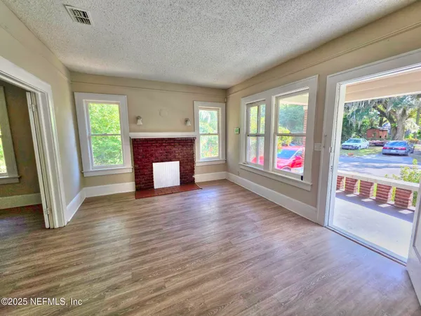an empty room with wooden floor fireplace and windows