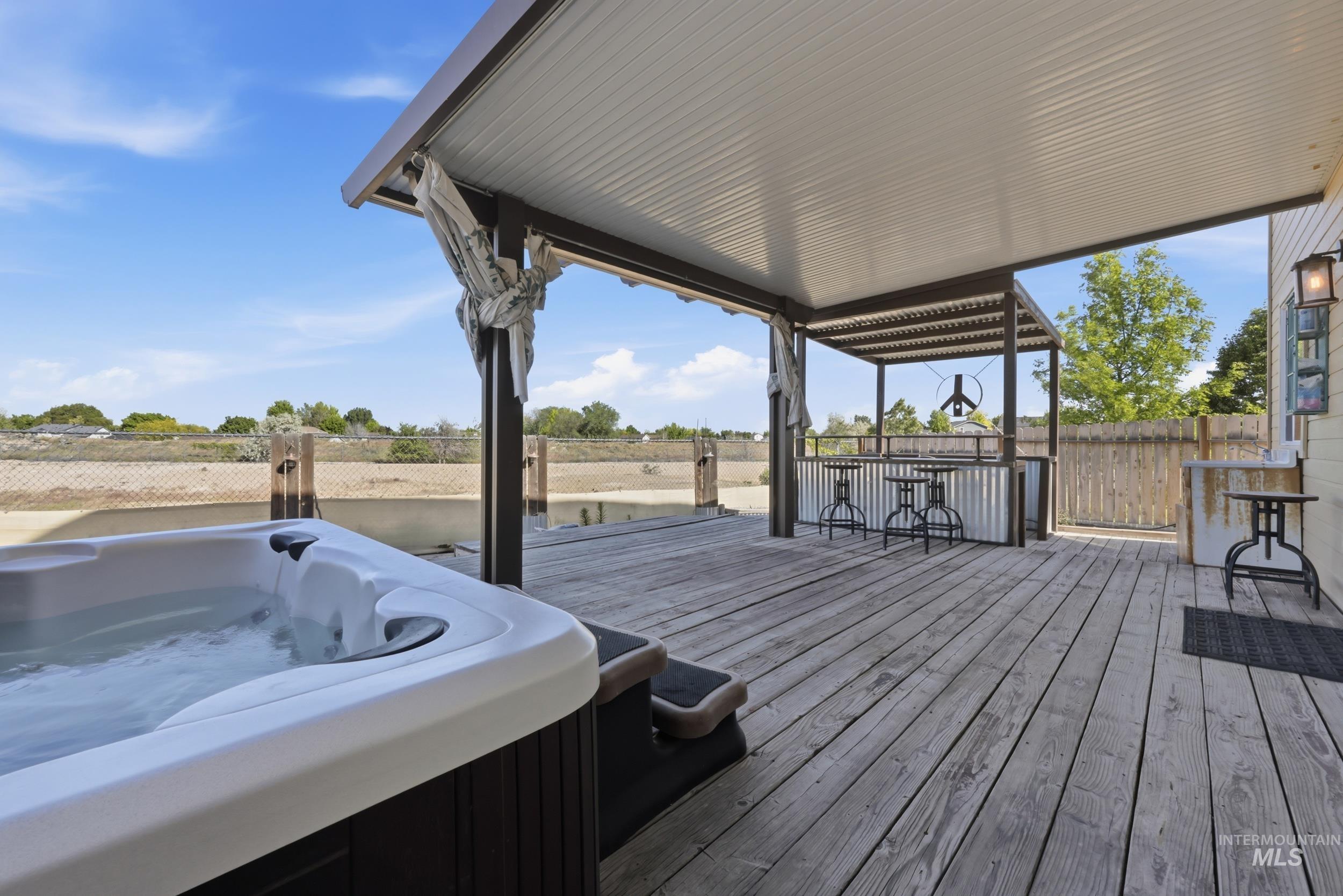 4855 South Chex Way Boise, ID 83709 - Photo 28 of 47 Spacious outdoor deck featuring a hot tub, covered patio, outdoor bar area with corrugated metal accents, and a privacy fence
