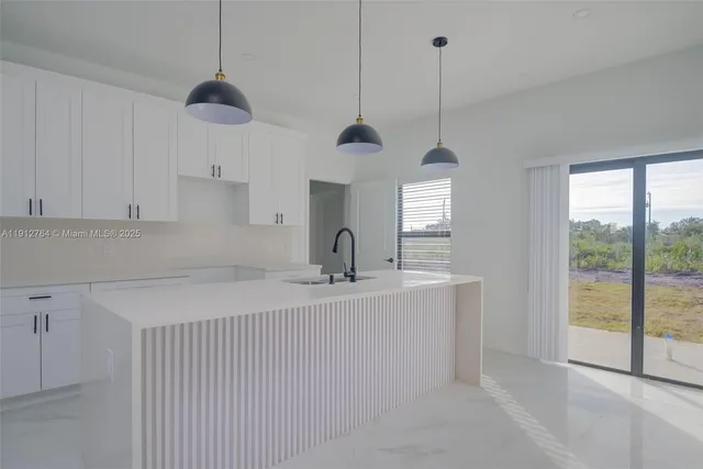 a kitchen with stainless steel appliances granite countertop a sink a window and white cabinets