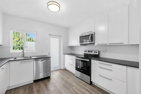 a kitchen with granite countertop a sink cabinets and stainless steel appliances