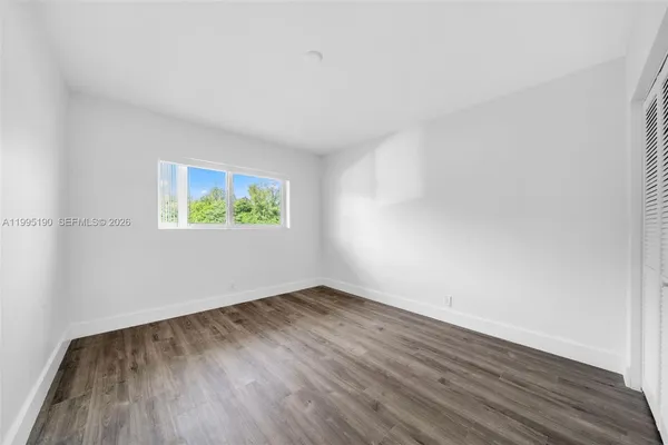 an empty room with wooden floor and window