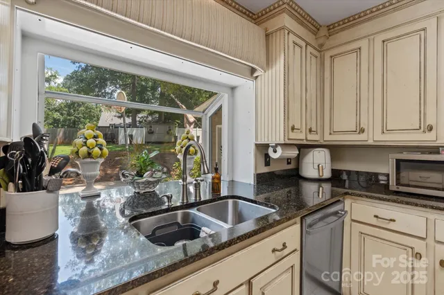 a kitchen with granite countertop a sink and a white wooden cabinets