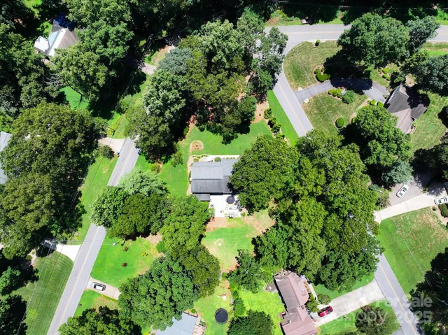 an aerial view of residential house with outdoor space and trees all around