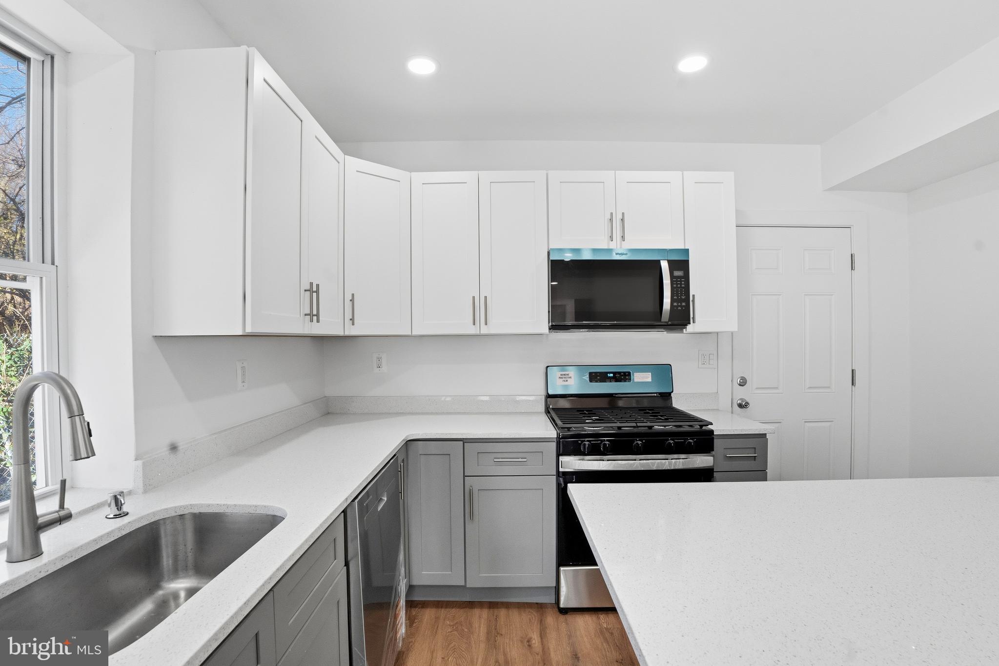 1281 Jackson Street Camden, NJ 08104 - Photo 15 of 43 a kitchen with granite countertop a sink and a stove top oven with wooden floor