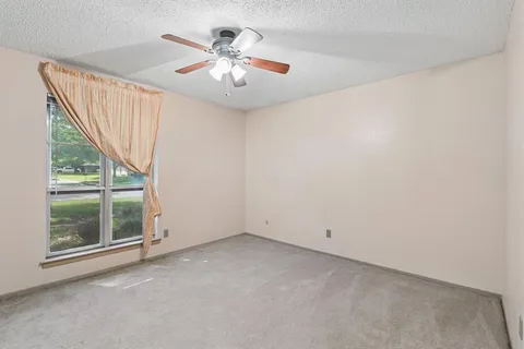 an empty room with windows and chandelier fan