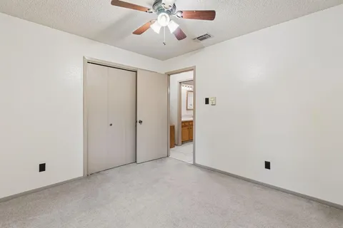 an empty room with chandelier fan and windows