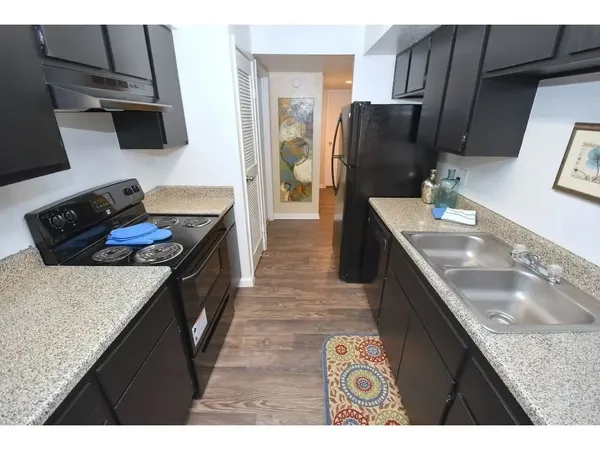 a kitchen with stainless steel appliances granite countertop a refrigerator a stove and a sink
