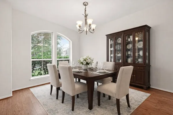 a dining room with wooden floor a chandelier a wooden table and chairs