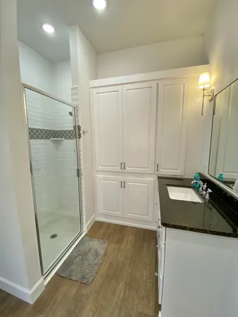 a bathroom with a granite countertop sink a mirror and shower