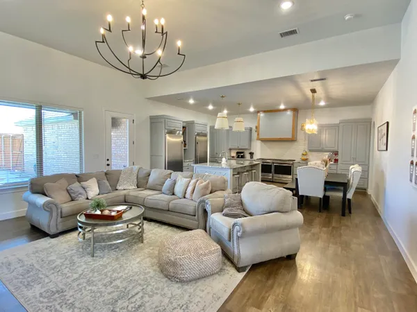 a living room with furniture kitchen view and a chandelier