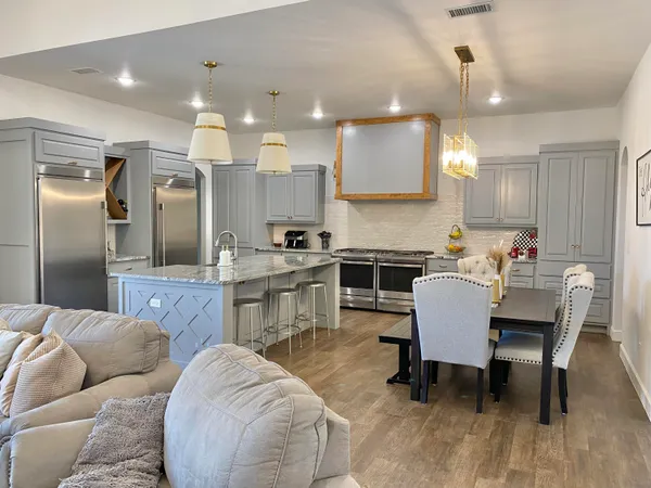 a kitchen with stainless steel appliances kitchen island granite countertop a refrigerator a stove a sink dishwasher with a dining table and chairs