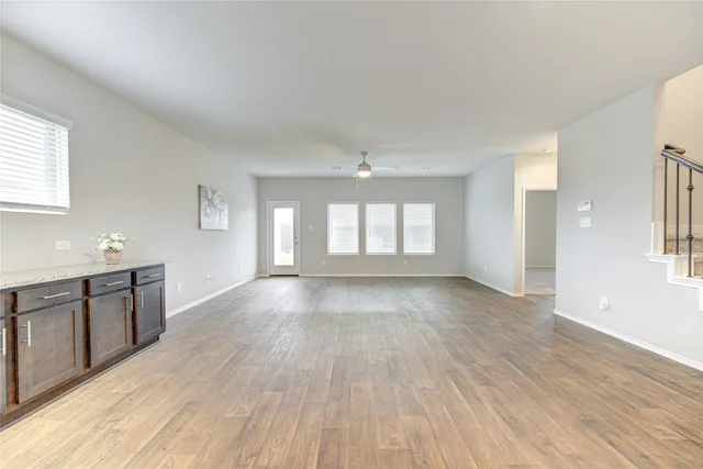 a view of an empty room with window and wooden floor