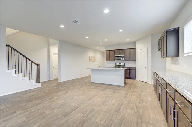 a large kitchen with a sink and dishwasher a stove top oven with wooden floor