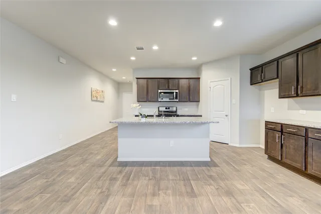 a view of kitchen with granite countertop refrigerator microwave sink and stove