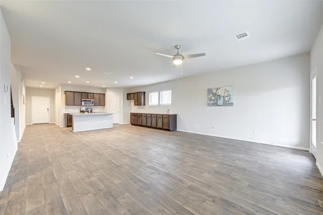 a view of empty room with wooden floor and kitchen view
