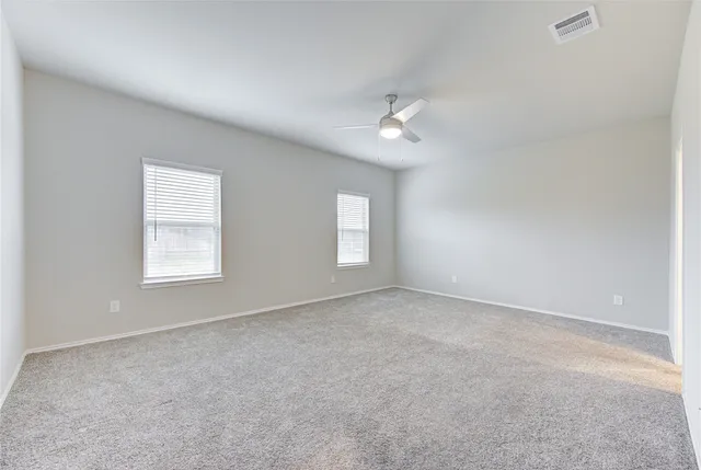 an empty room with a window and ceiling fan