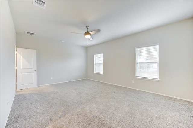 an empty room with windows and fan