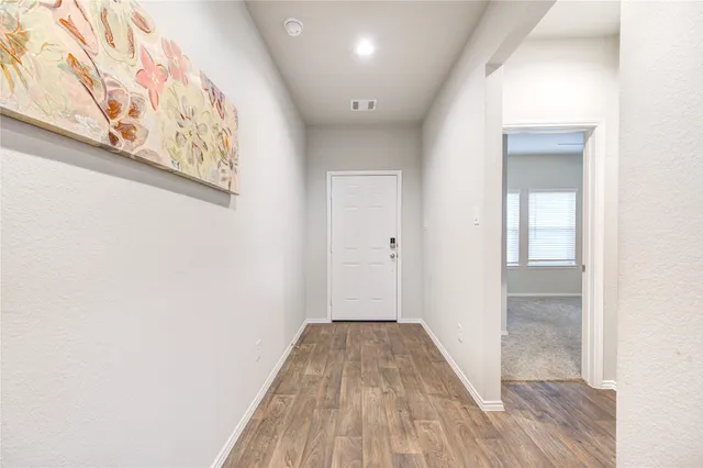 a view of a hallway with wooden floor and a bathroom