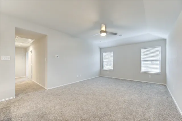 an empty room with windows and ceiling fan
