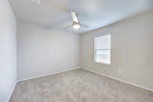 an empty room with a window and ceiling fan