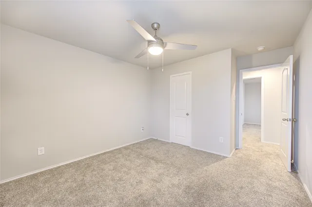 an empty room with closet and a ceiling fan