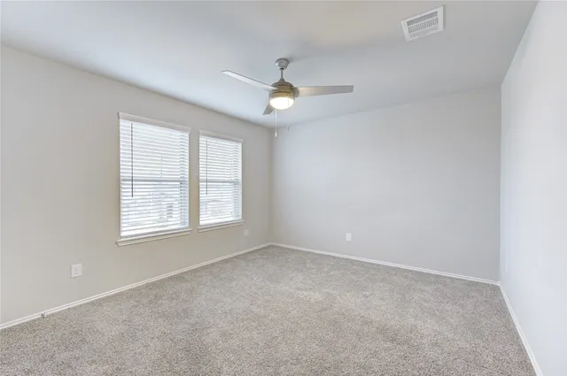 an empty room with ceiling fan and window