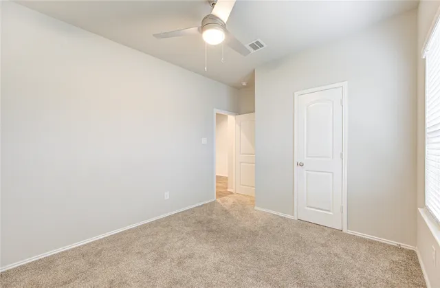 an empty room with closet and a chandelier fan
