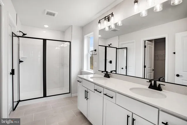 a bathroom with a double vanity sink mirror and shower