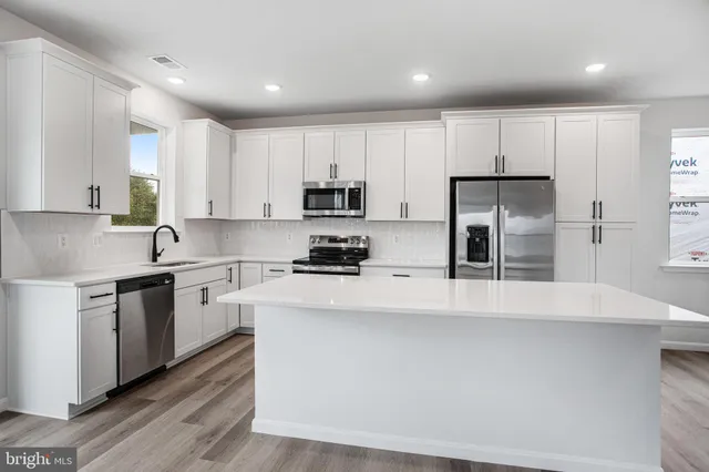 a kitchen with stainless steel appliances a refrigerator sink and white cabinets