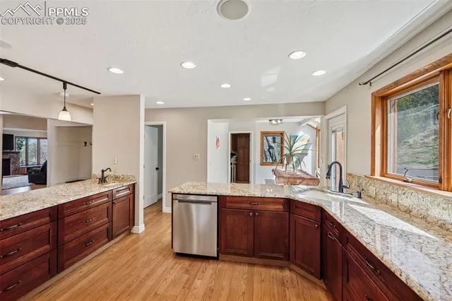 a large kitchen with granite countertop a sink dishwasher stove and wooden cabinets