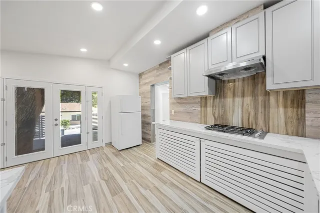 a kitchen with stainless steel appliances wooden floor and a large window