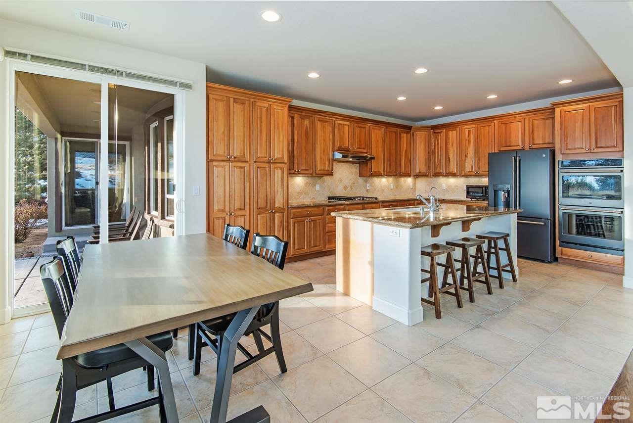6965 Cour Street Reno, NV 89511 - Photo 5 of 25 a kitchen with stainless steel appliances kitchen island granite countertop a table chairs sink and cabinets