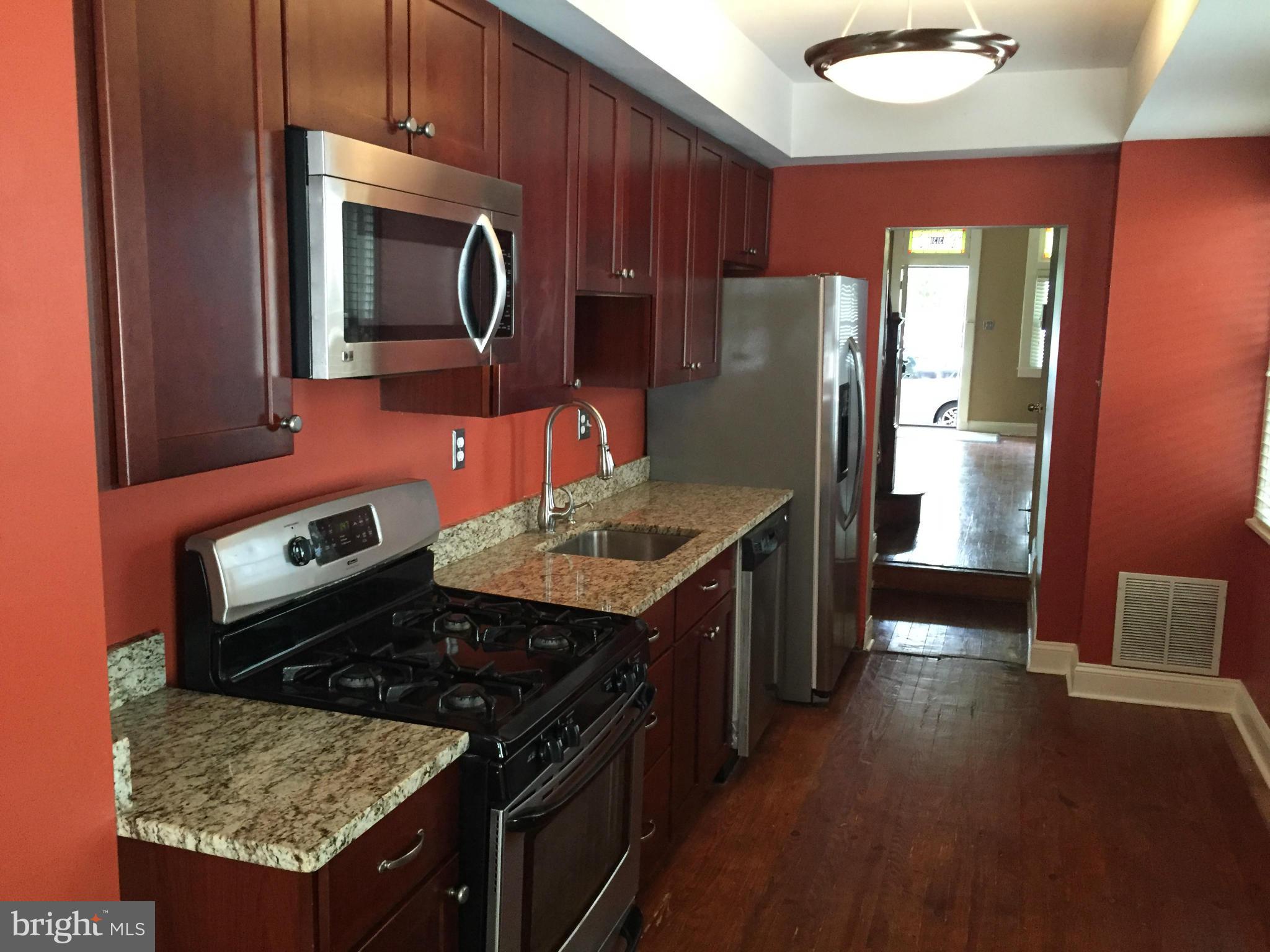 3131 Elliott Street Baltimore, MD 21224 - Photo 5 of 14 a kitchen with granite countertop wooden cabinets and stainless steel appliances