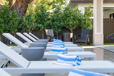 a view of a patio with couches table and chairs with wooden fence and plants