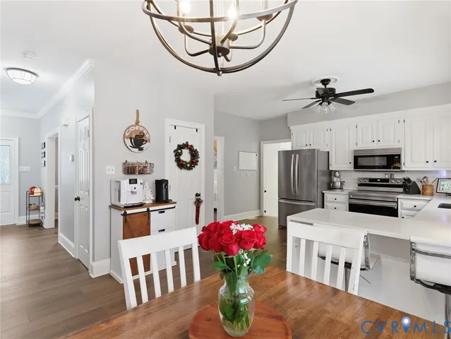 a kitchen with stainless steel appliances kitchen island granite countertop a refrigerator a stove a sink dishwasher a dining table and chairs with wooden floor