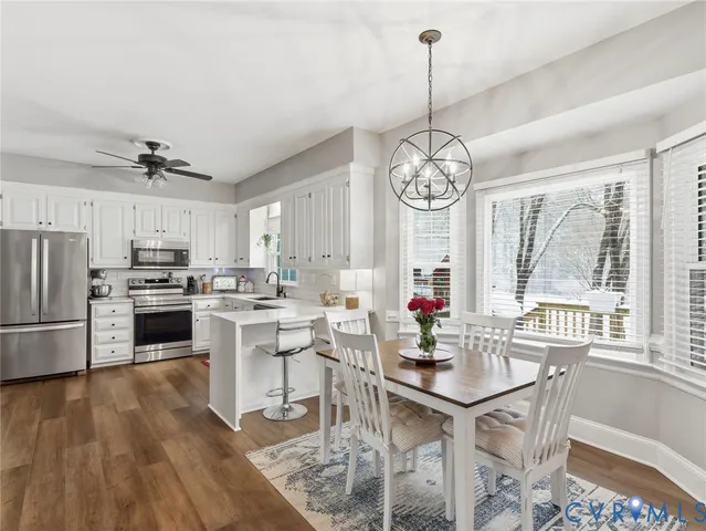 a very nice looking open dining room with a large window a chandelier