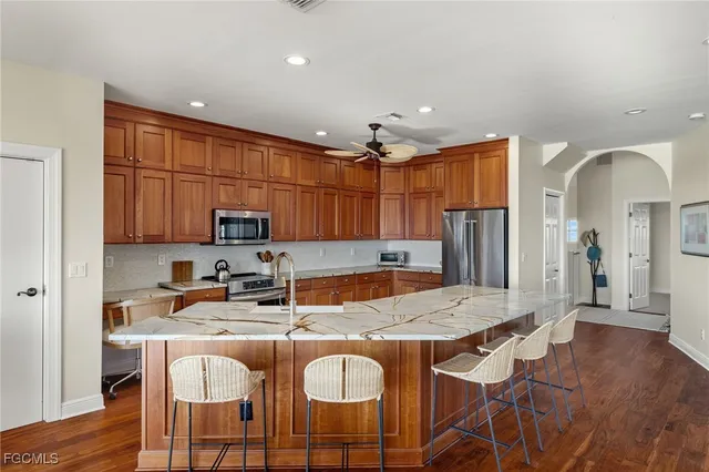 a kitchen with granite countertop a table chairs microwave and refrigerator