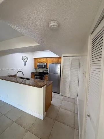 a kitchen with stainless steel appliances granite countertop a sink and a refrigerator