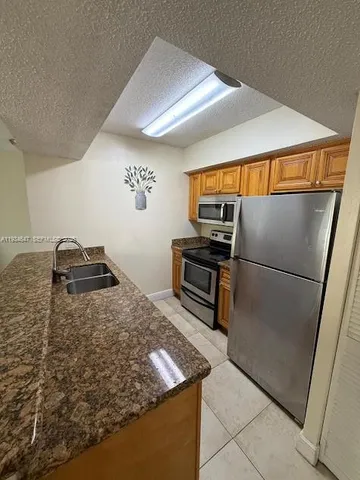 a kitchen with stainless steel appliances granite countertop a refrigerator and a stove