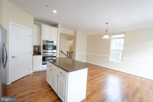 a kitchen with stainless steel appliances granite countertop a sink a stove a refrigerator cabinets and wooden floor