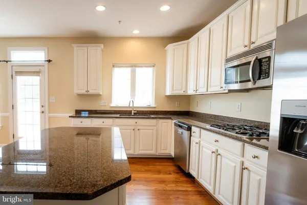 a kitchen with stainless steel appliances granite countertop a stove a sink and a microwave
