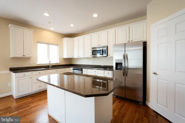 a kitchen with kitchen island granite countertop a sink appliances and cabinets