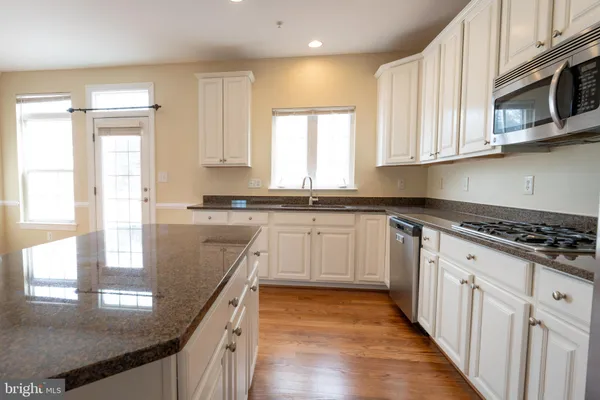 a kitchen with stainless steel appliances granite countertop a stove a sink and a microwave