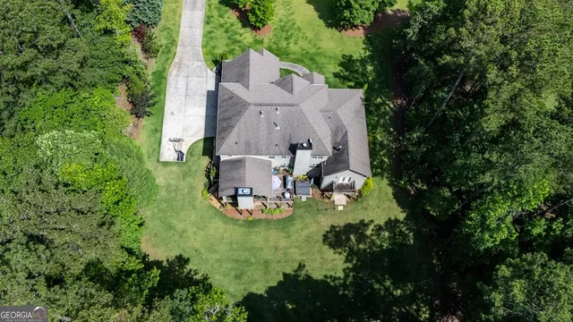 an aerial view of a house with garden space and trees all around