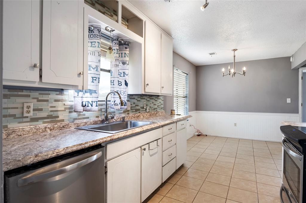 1106 HCR 1414 Covington, TX 76636 - Photo 12 of 37 a kitchen with a sink dishwasher a stove and white cabinets with wooden floor