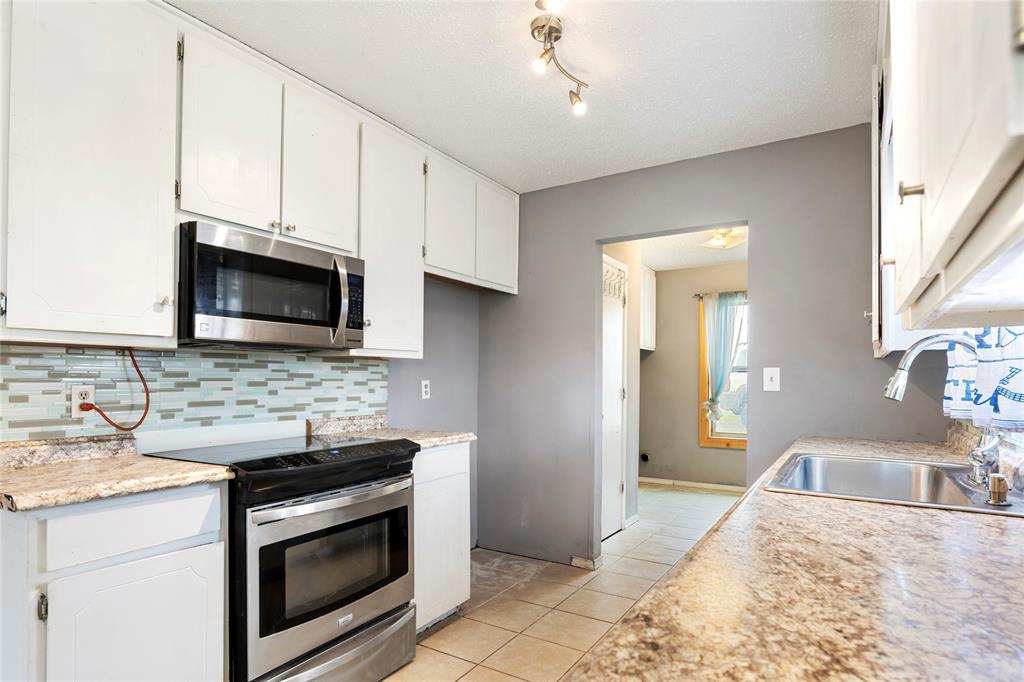 1106 HCR 1414 Covington, TX 76636 - Photo 14 of 37 a kitchen with stainless steel appliances granite countertop a sink stove and microwave