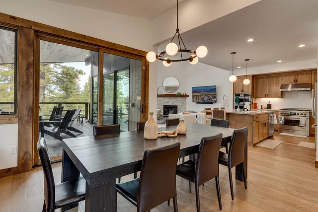 a kitchen with stainless steel appliances kitchen island granite countertop a refrigerator a stove a sink a dining table and chairs with wooden floor