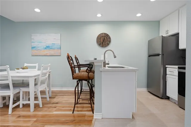 a kitchen with stainless steel appliances kitchen island granite countertop a table chairs and a refrigerator
