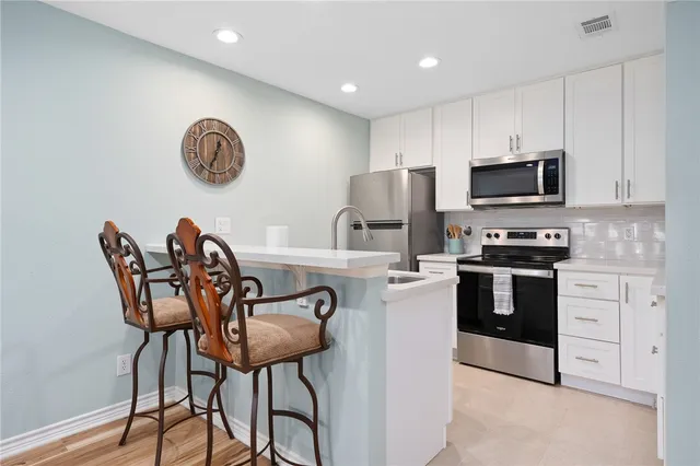 a kitchen with stainless steel appliances granite countertop a stove top oven a sink a dining table and chairs