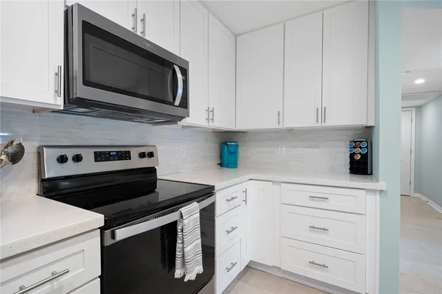 a kitchen with white cabinets and black appliances